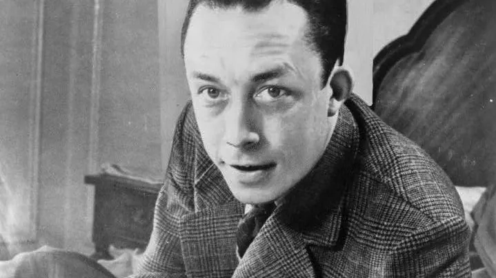 Albert Camus, masasında otururken (1957)